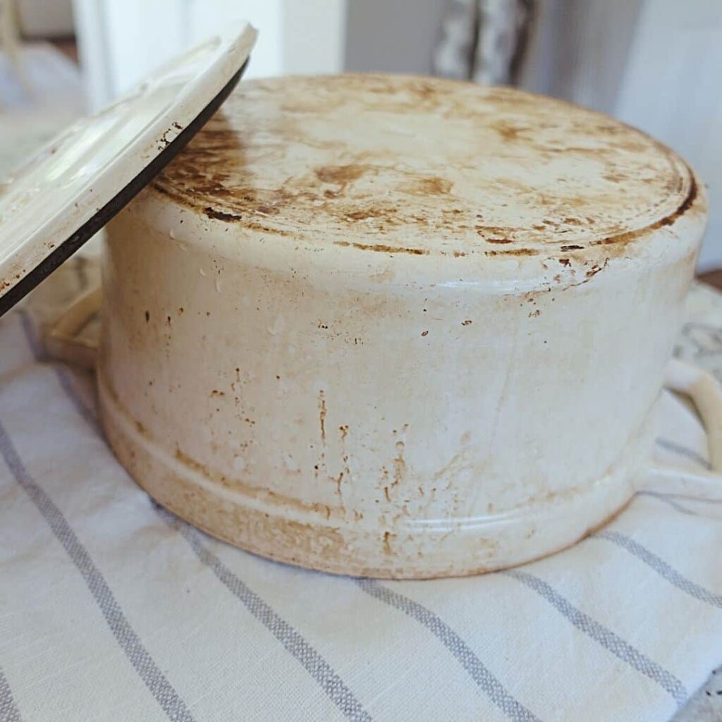 burnt enameled dutch oven upsidedown on a striped tea towel