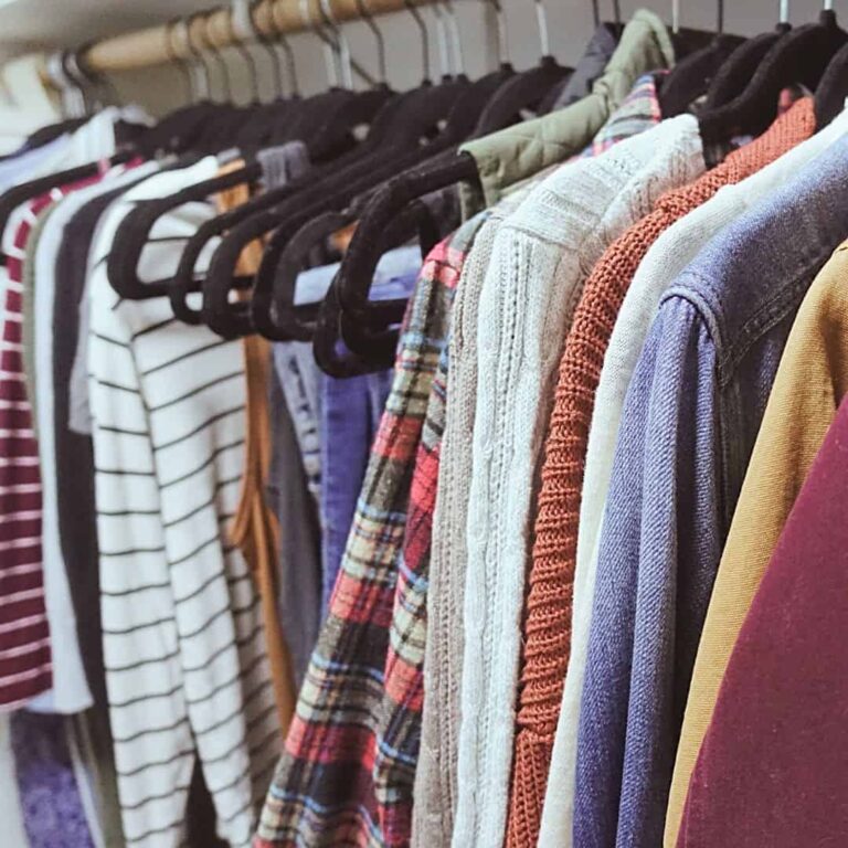 autumn capsule wardrobe hanging clothes in closet with striped shirts orange jackets flannel shirt