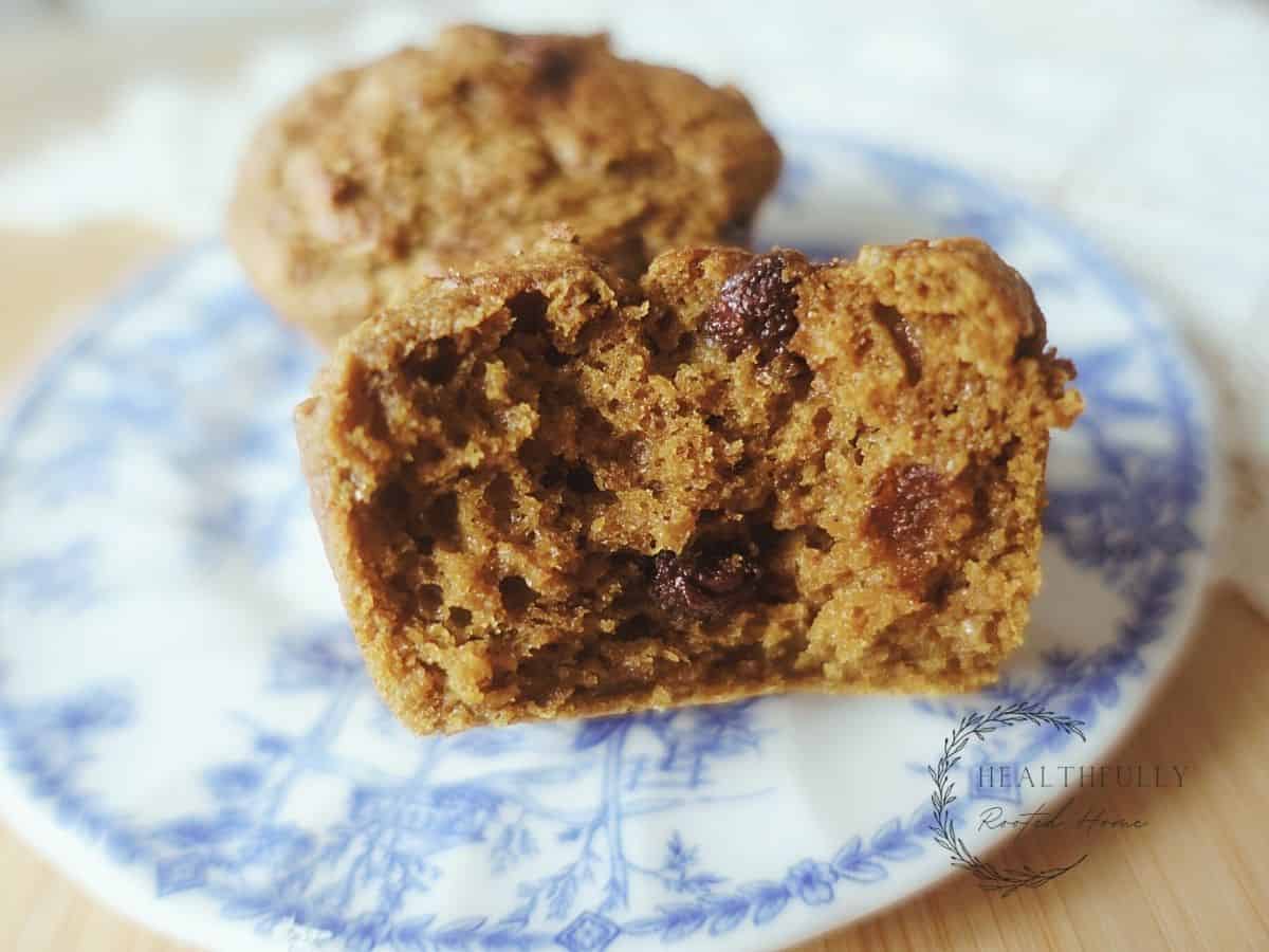 sourdough pumpkin muffin inside with chocolate chips peaking through sitting on blue and white china