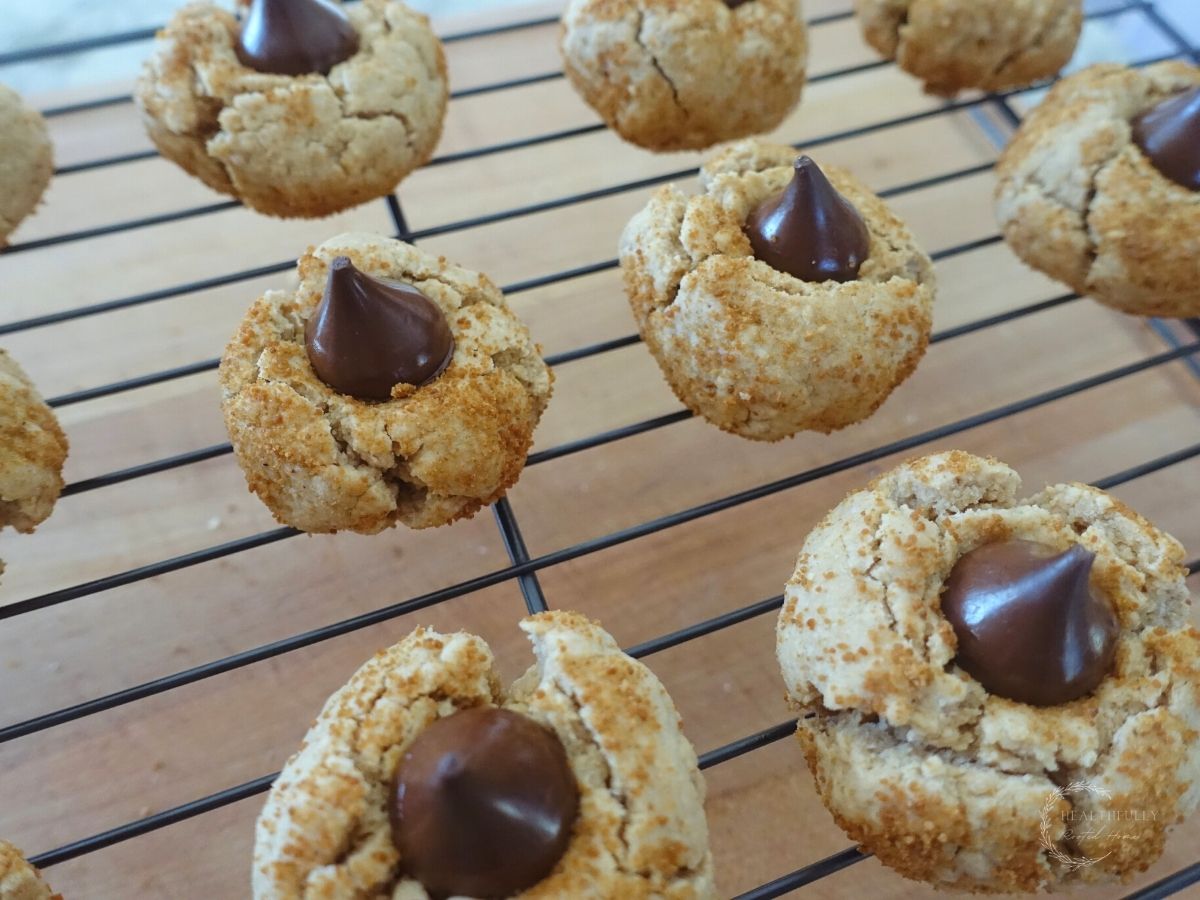 peanut kisses on a wire cooling rack with a wooden cutting board underneath