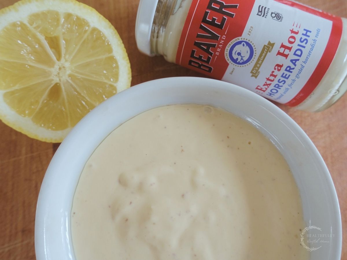 horseradish aioli sauce in a white dish with a lemon on the side and a bottle of beaver prepared horseradish