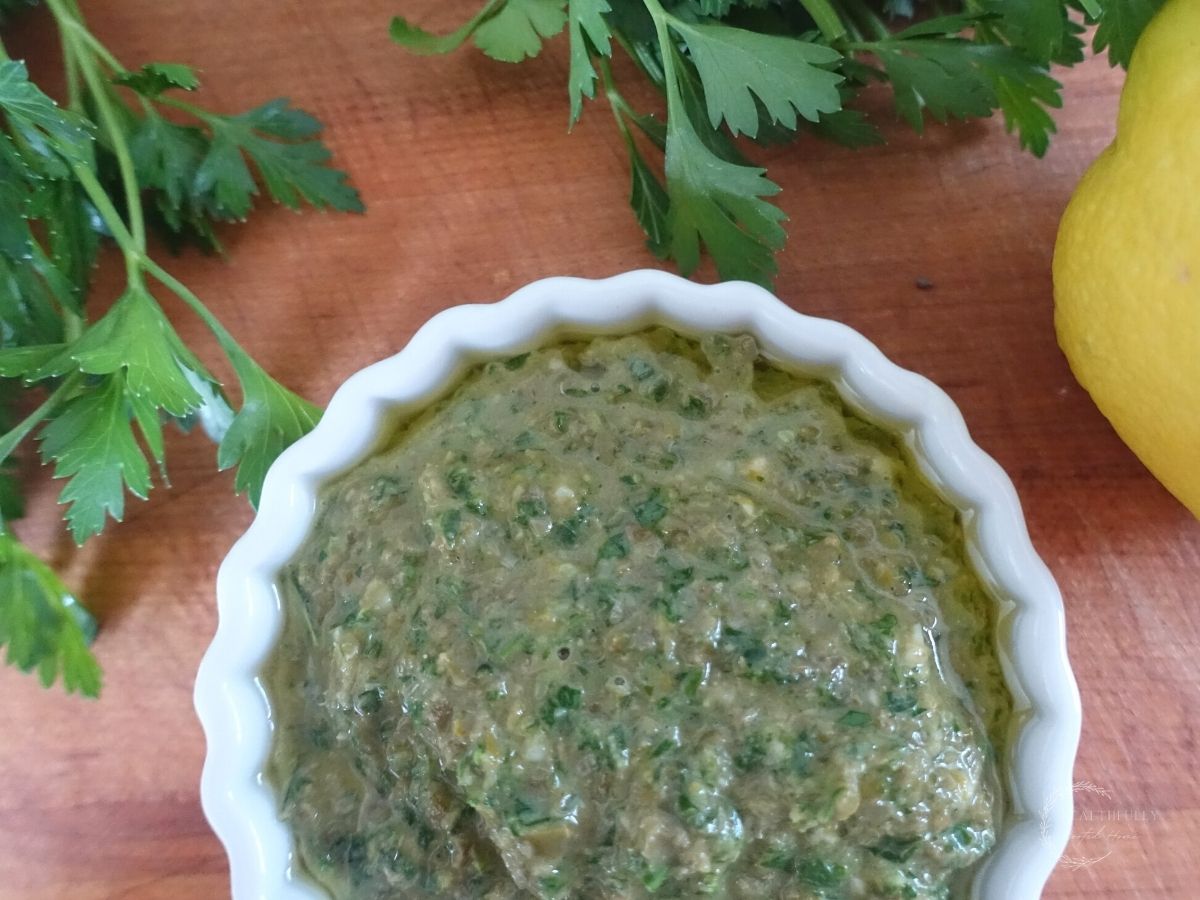 salsa gremolata in a white dish with italian flat leaf parsley and a lemon next to it