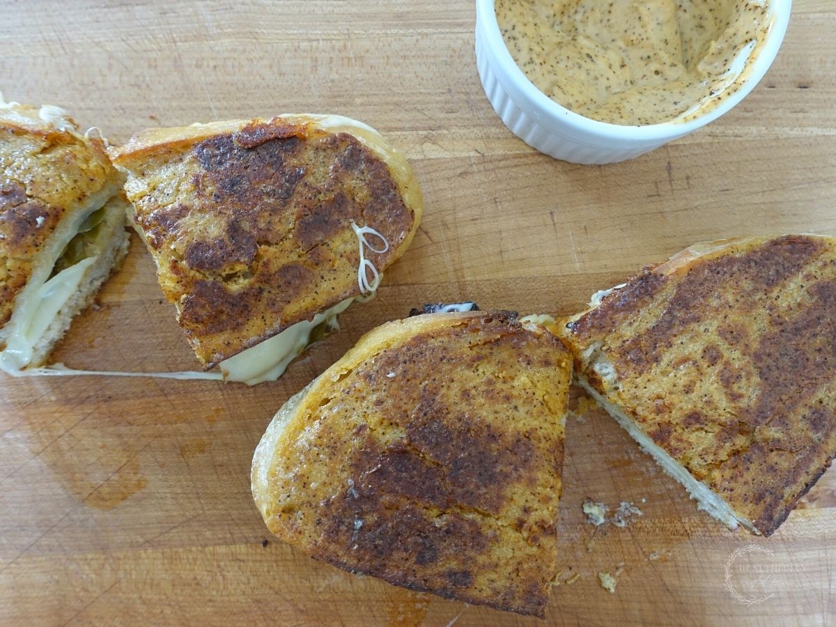 ancho aioli grilled cheese sandwiches made without butter laying flat on a wooden cutting board next to a bowl of ancho aioli