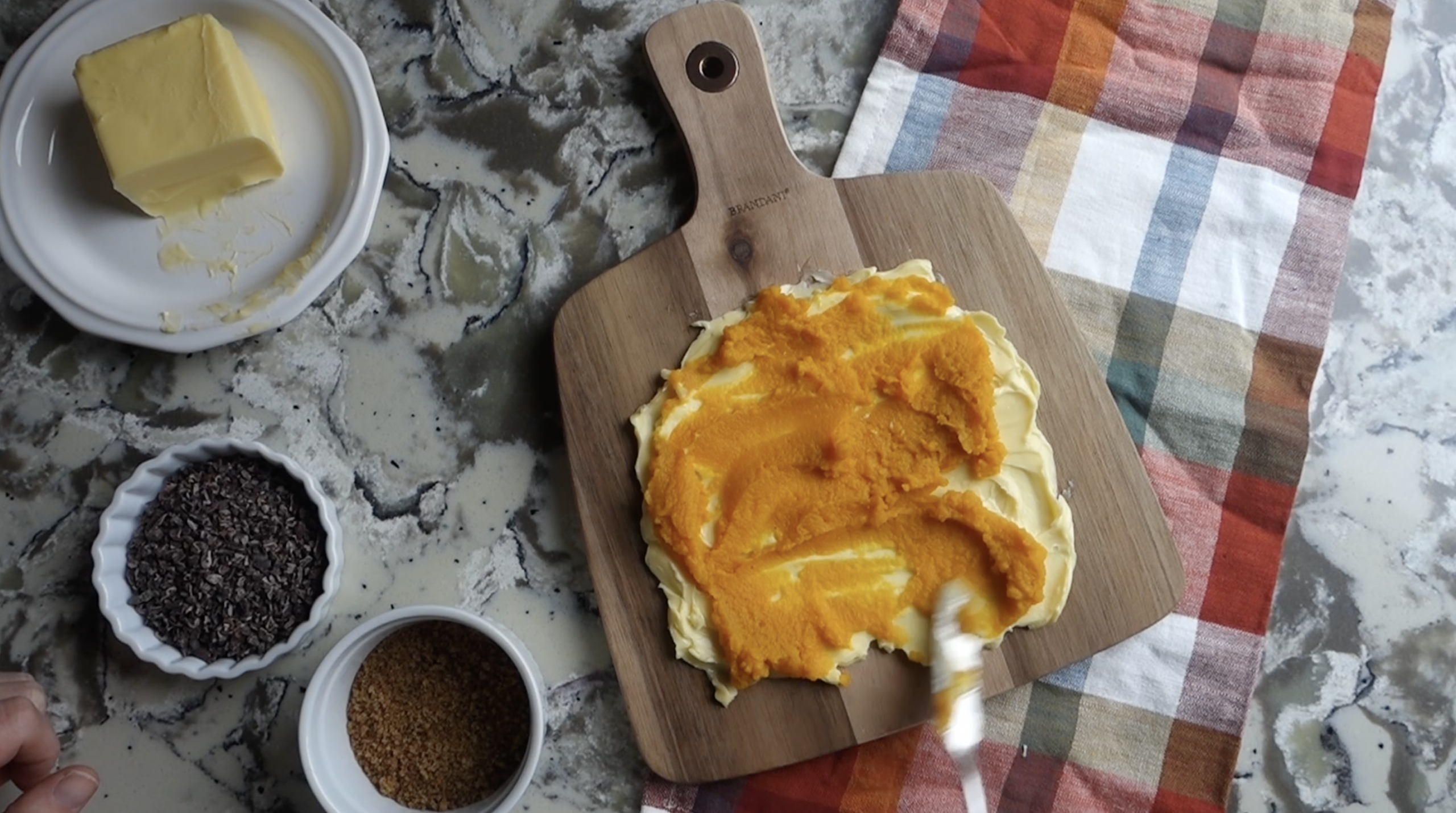 spreading pumpkin puree on top of the butter for a pumpkin butter board