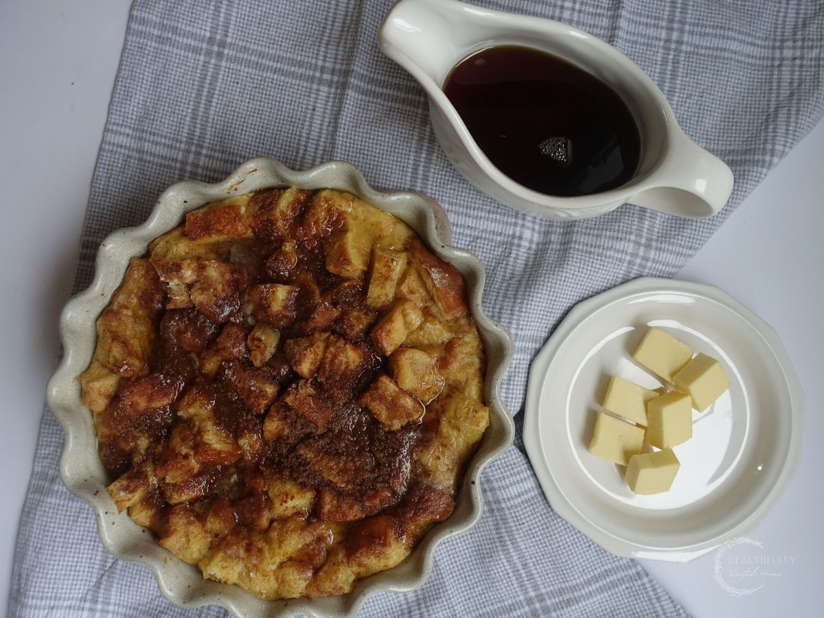 brioche french toast casserole with pads of butter and maple syrup on the side in a flat lay format