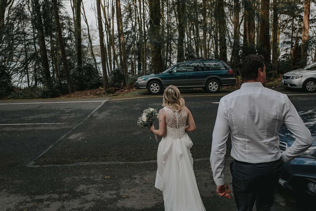 groom and bride newly married on their way to their green subaru to start their lives together.