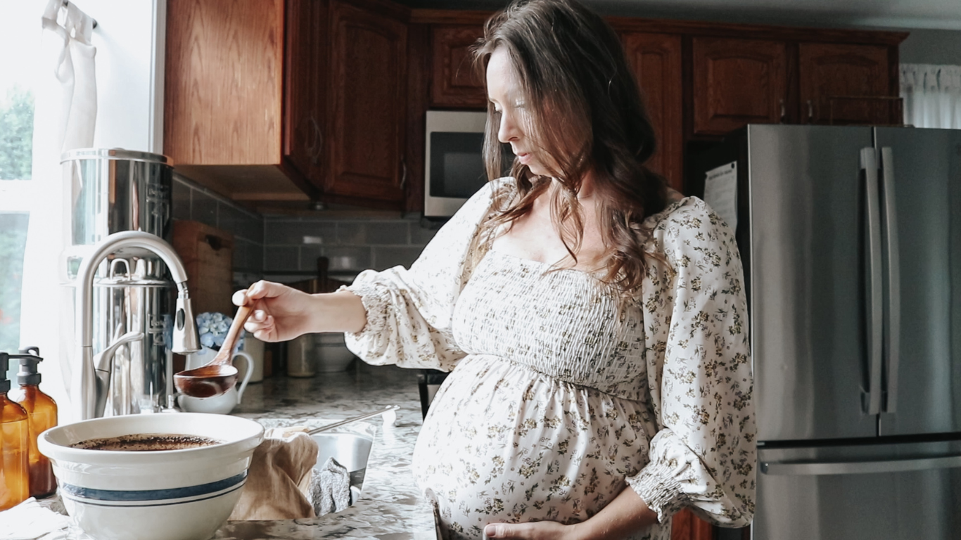 pregnant homemaker making bone broth wearing a long dress