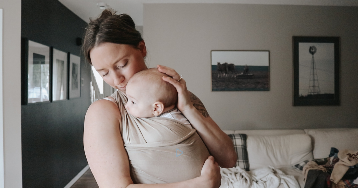 mother with her baby in a baby wrap kissing his head