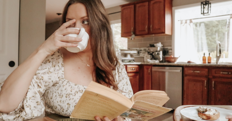 homemaker in a dress reading a book drinking coffee