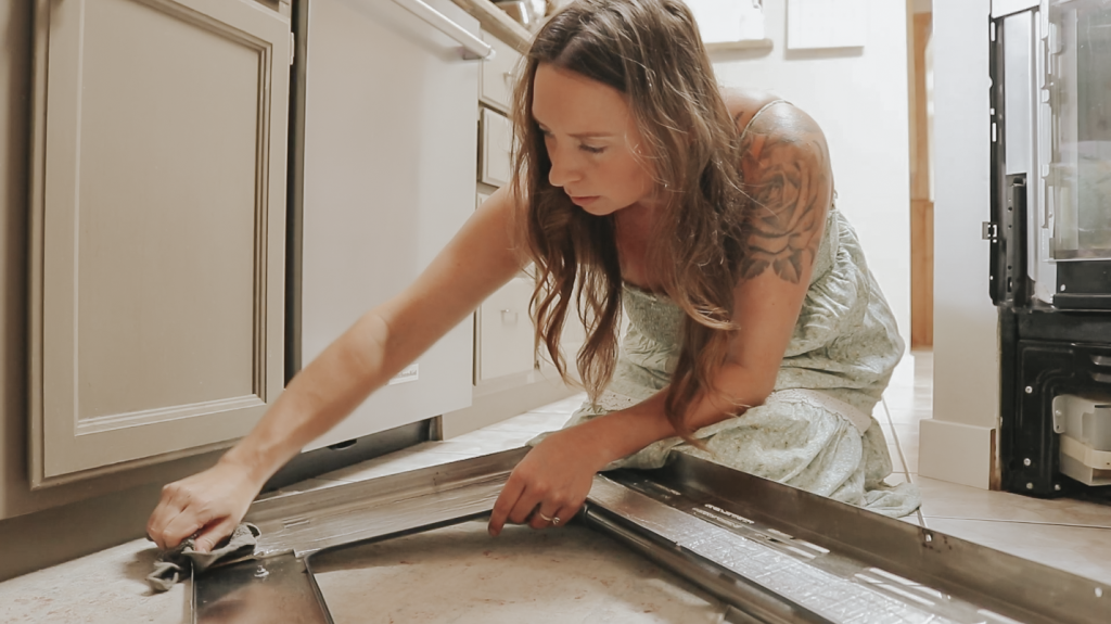 Christian homemaker wearing a light green dress is cleaning the inside of her oven.