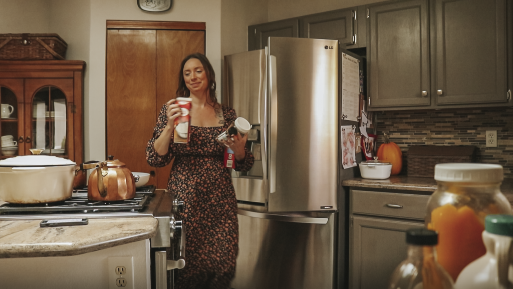 Christian homemaker wearing a black floral dress is walking from her pantry to the kitchen counter with ingredients in her hands.