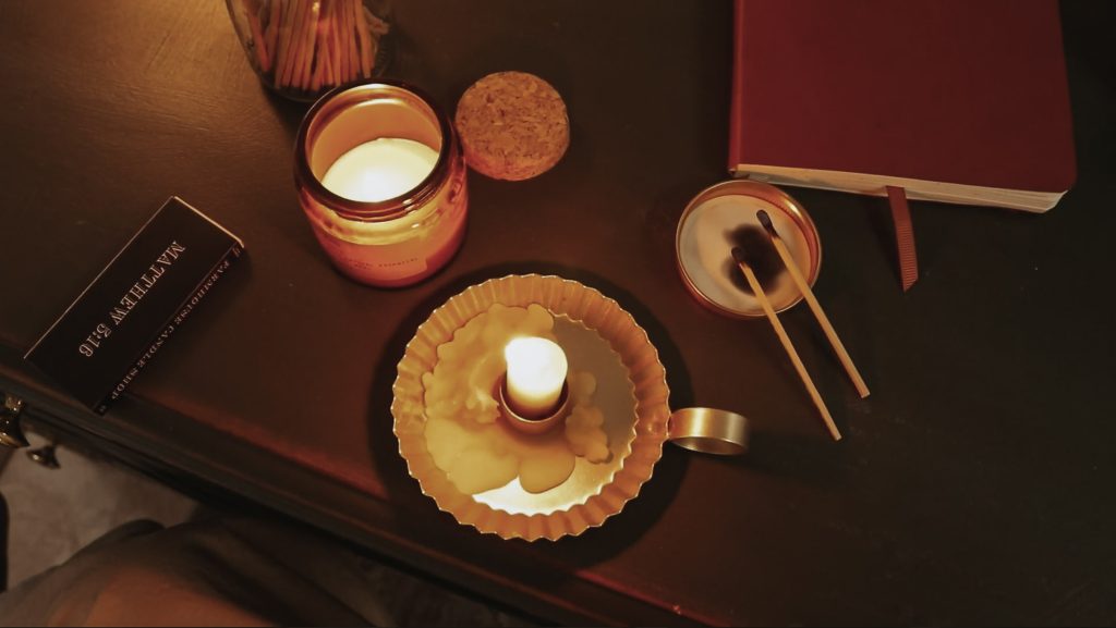 Shot of candles and matches with a book sitting on a wooden desk.