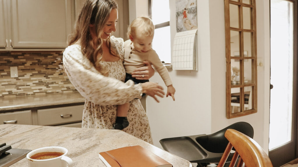 Christian homemaker holds baby in kitchen.
