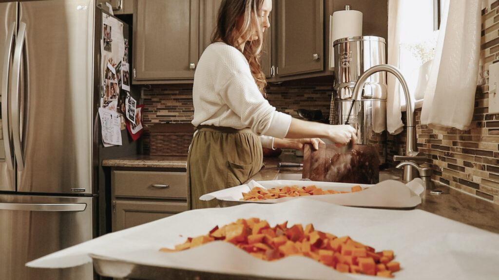 Homemaker puts water in large, stainless steel pot at kitchen sink.