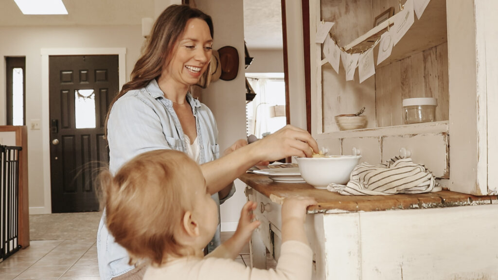 Homemaker and mother smiles while making cookies with her baby.