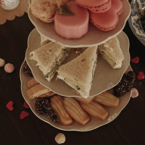 Tiered tray holds desserts on wooden dining room table.