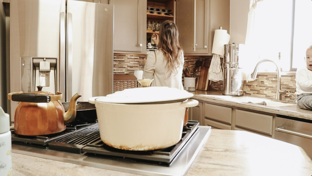 Christian homemaker takes ingredients out of cabinet in kitchen.