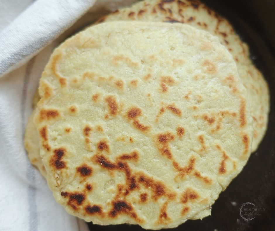 einkorn sourdough tortillas stacked on top of each other in a cast iron skillet
