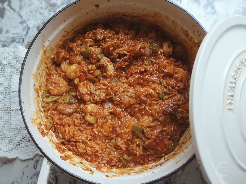 jambalaya in a dutch oven with the lid leaning on the edge