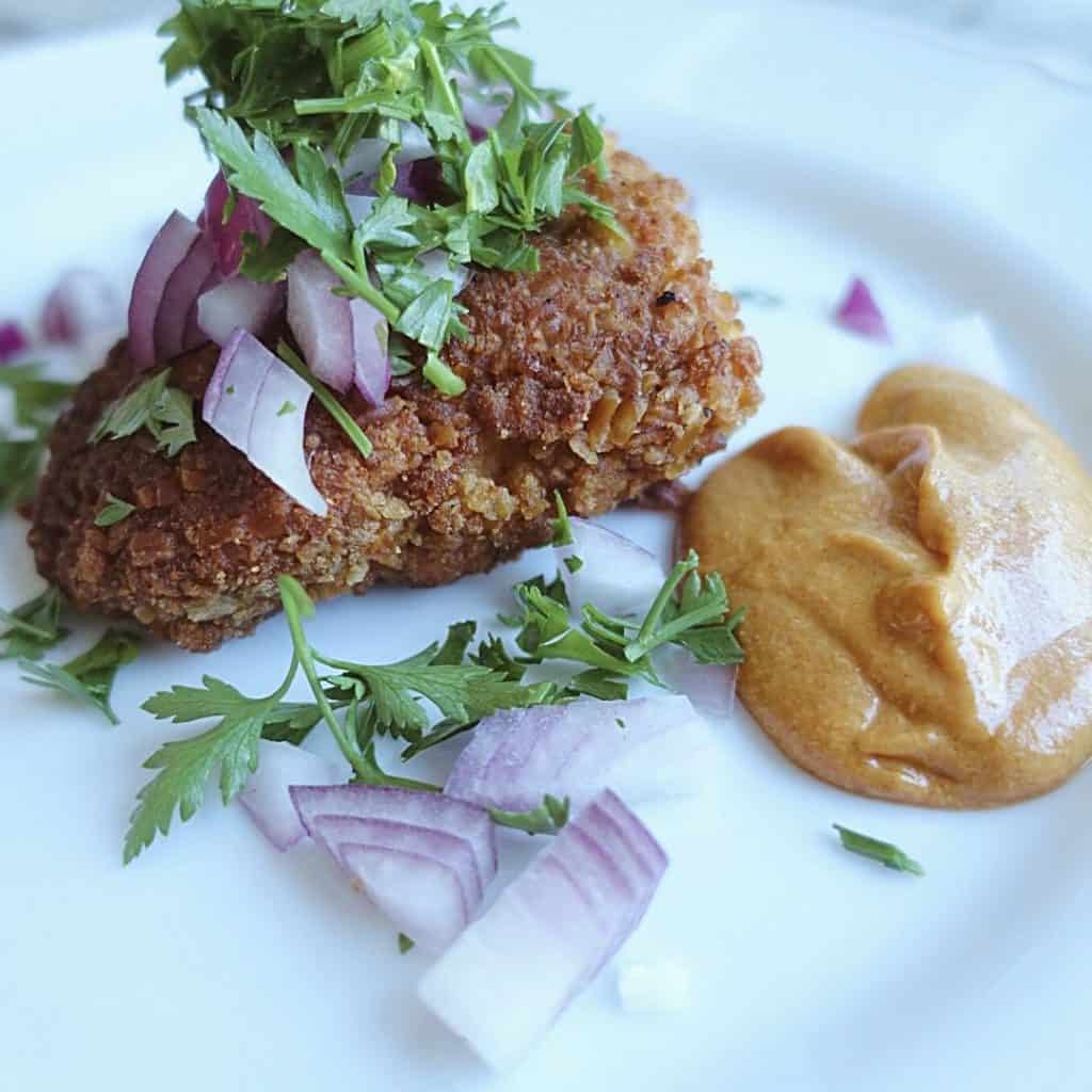 crispy cast iron pretzel chicken with red onion and parsley on top