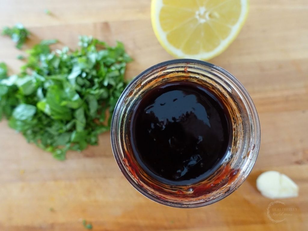 balsamic fig glaze in a small mason jar with chopped basil lemon and garlic surrounding it