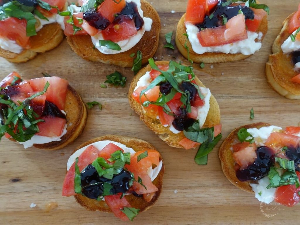 crostini with burrata and tomatoes topped with fresh basil on a wooden cutting board