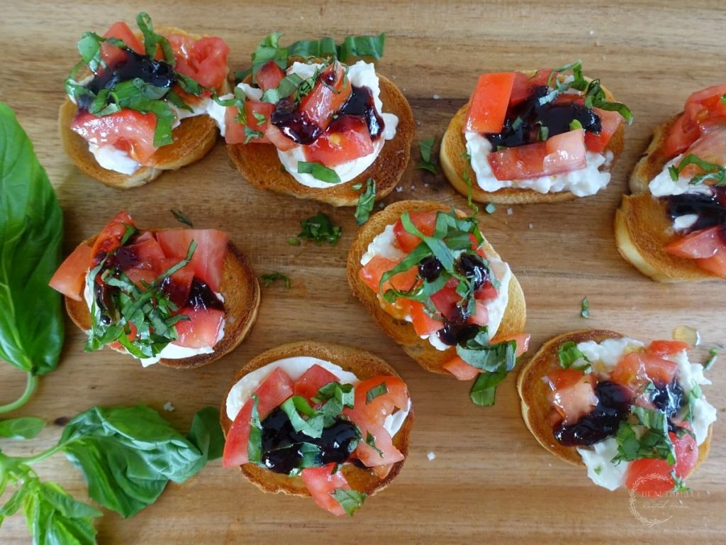 burrata bruschetta italiana on a wooden cutting board with basil leaves on the side