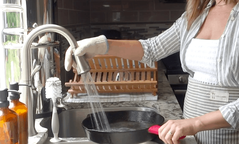cleaning a cast iron skillet with water ove glove and rubber cast iron protector