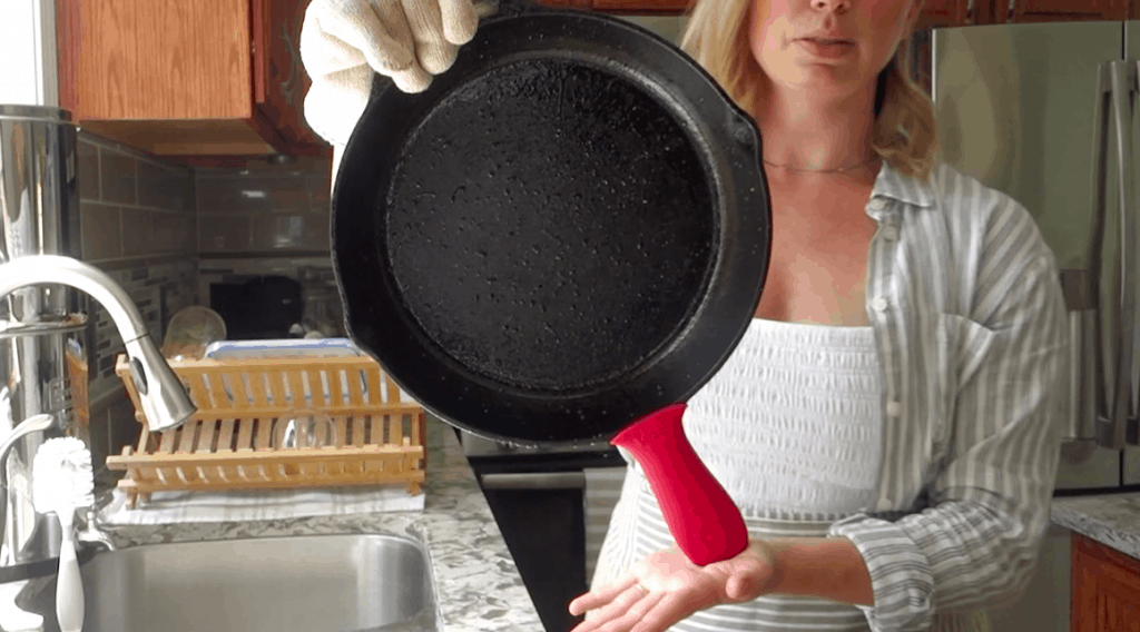 clean and cast iron skillet held up with ove glove and rubber cast iron protector