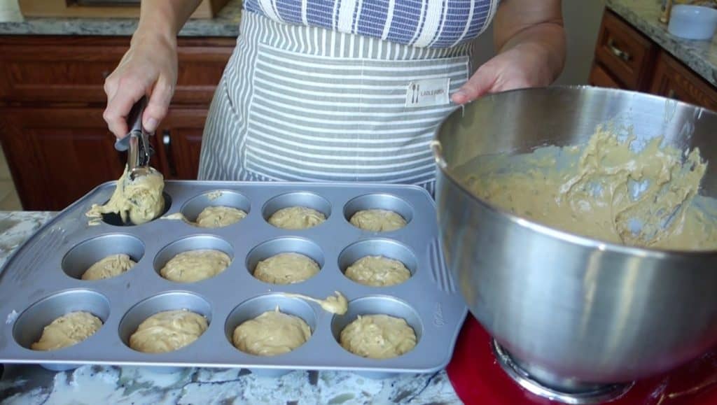 scooping lemon and lavender sourdough discard muffins into a muffin tin