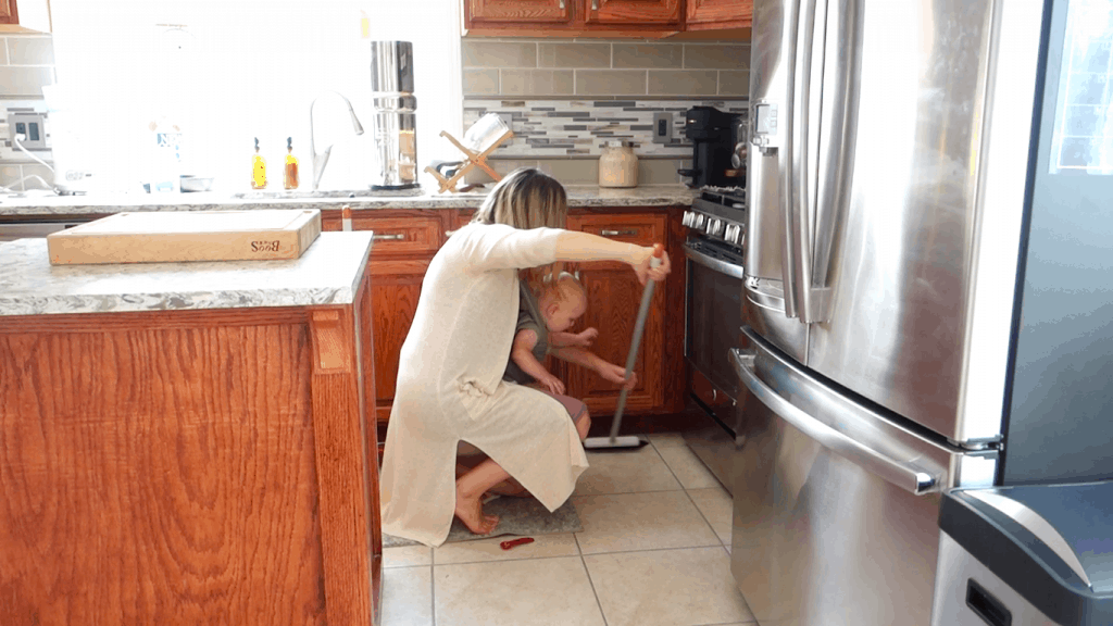 sweeping in the corners while doing autumn clean while babywearing in a boba wrap