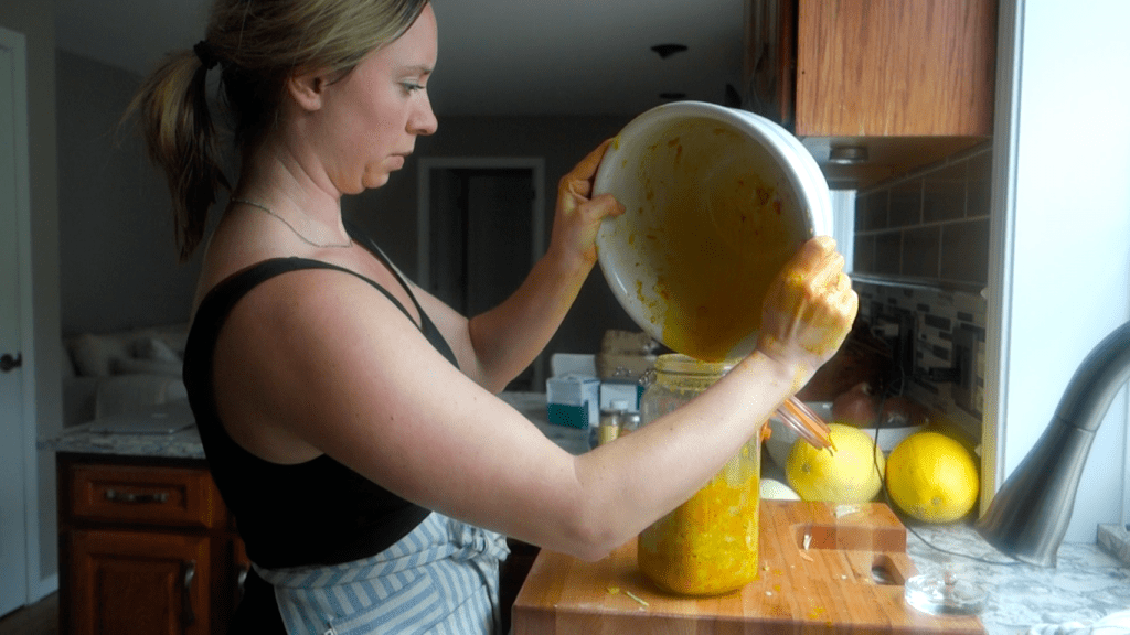 dumping the brine into the fermenting jar of the curry kraut