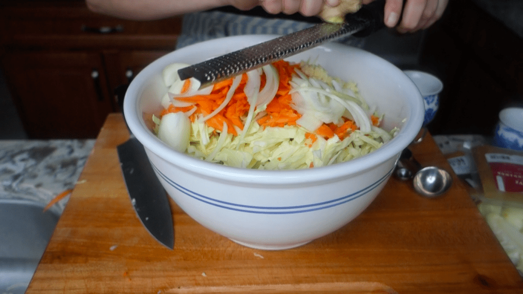 grating ginger into the bowl of curry kraut ingredients