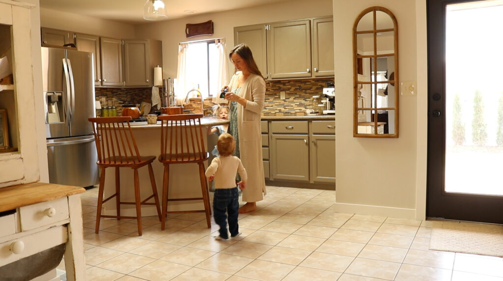 A homemaker in her pale green dress helps her young son in her kitchen.