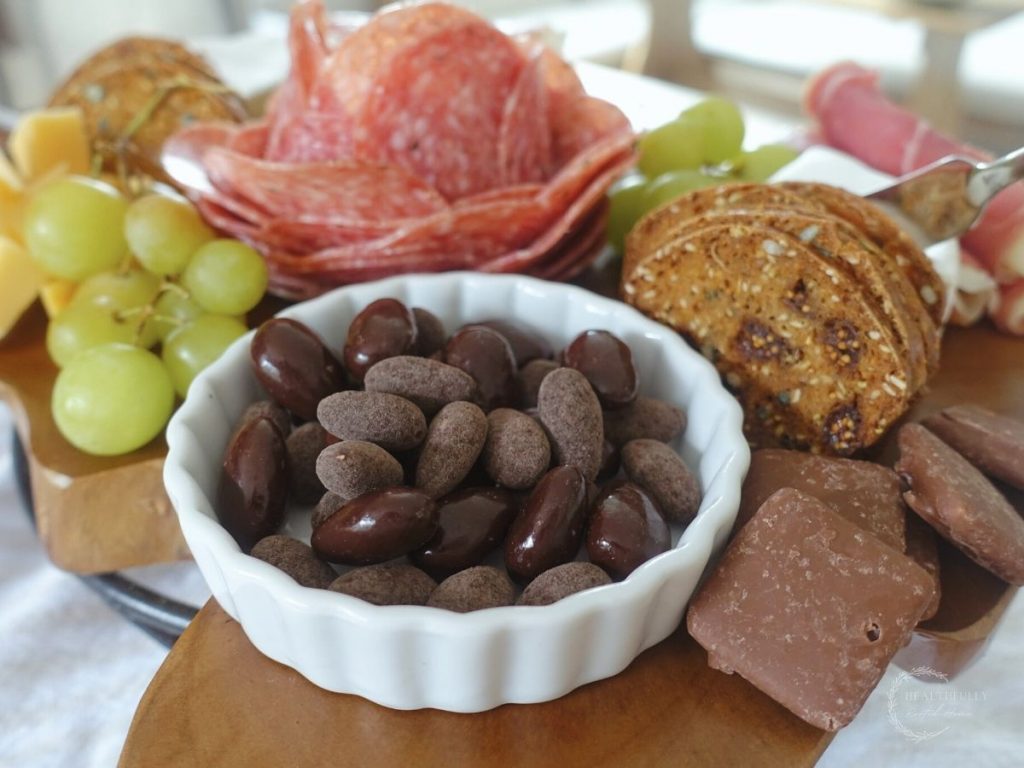 charcuterie board with a ramekin of chocolate covered almonds