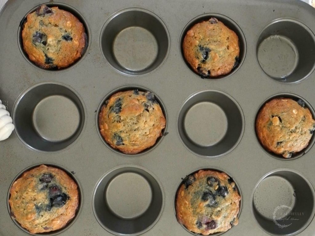 baked banana blueberry oatmeal muffins in a muffin tin with spaces in between each muffin