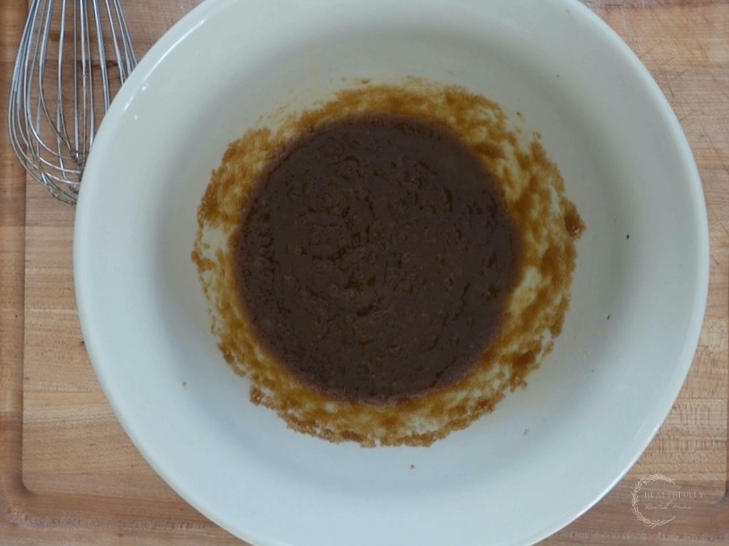 butter and sugars mixed in a bowl with a whisk on the side
