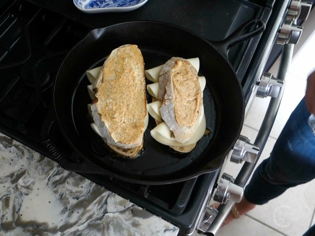 top slices of bread with ancho aioli on top added to the grilled cheese sandwiches in the cast iron skillet showing an alternative to making grilled cheese without butter