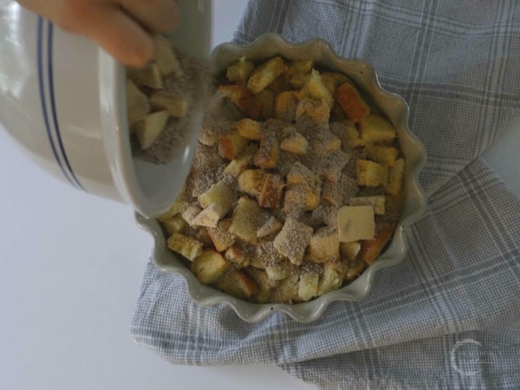 sprinkling crumble topping over custard soaked brioche bread in a casserole dish