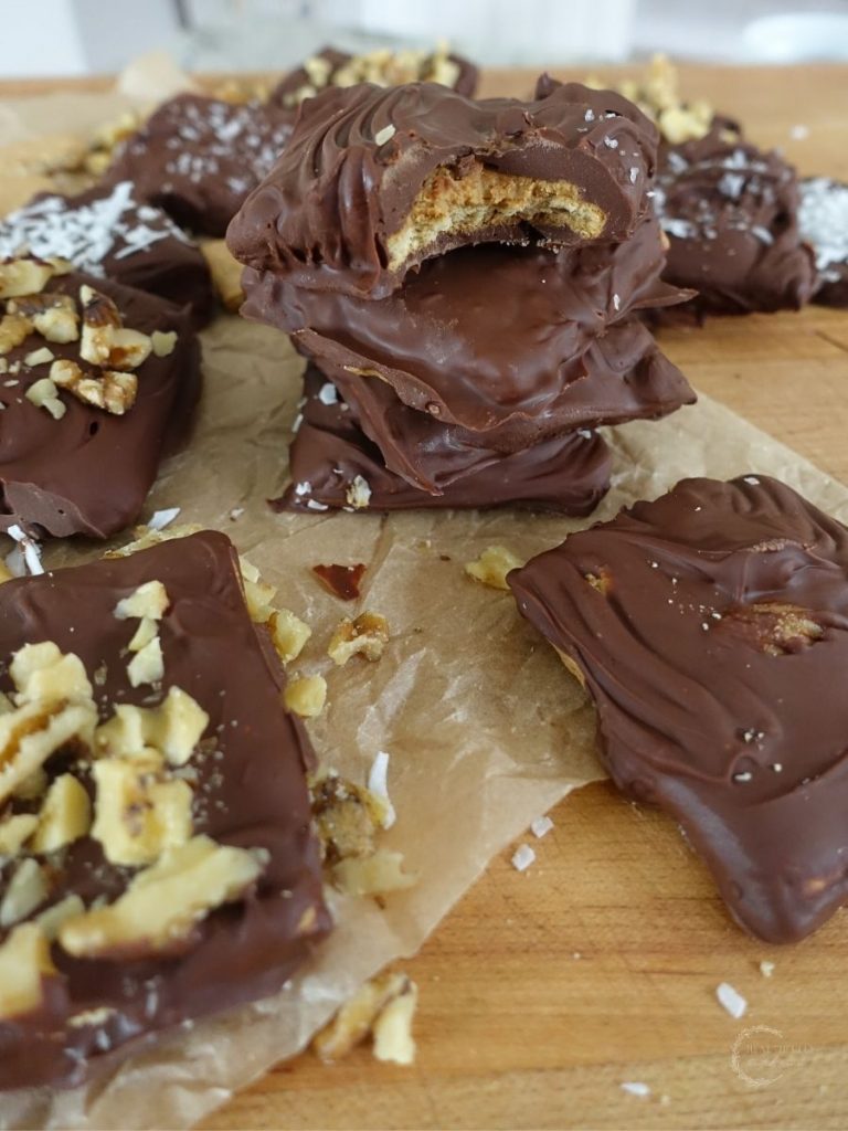 chocolate covered graham cracker with peanut butter inside stacked on top eachother with walnut topped grahams next to it