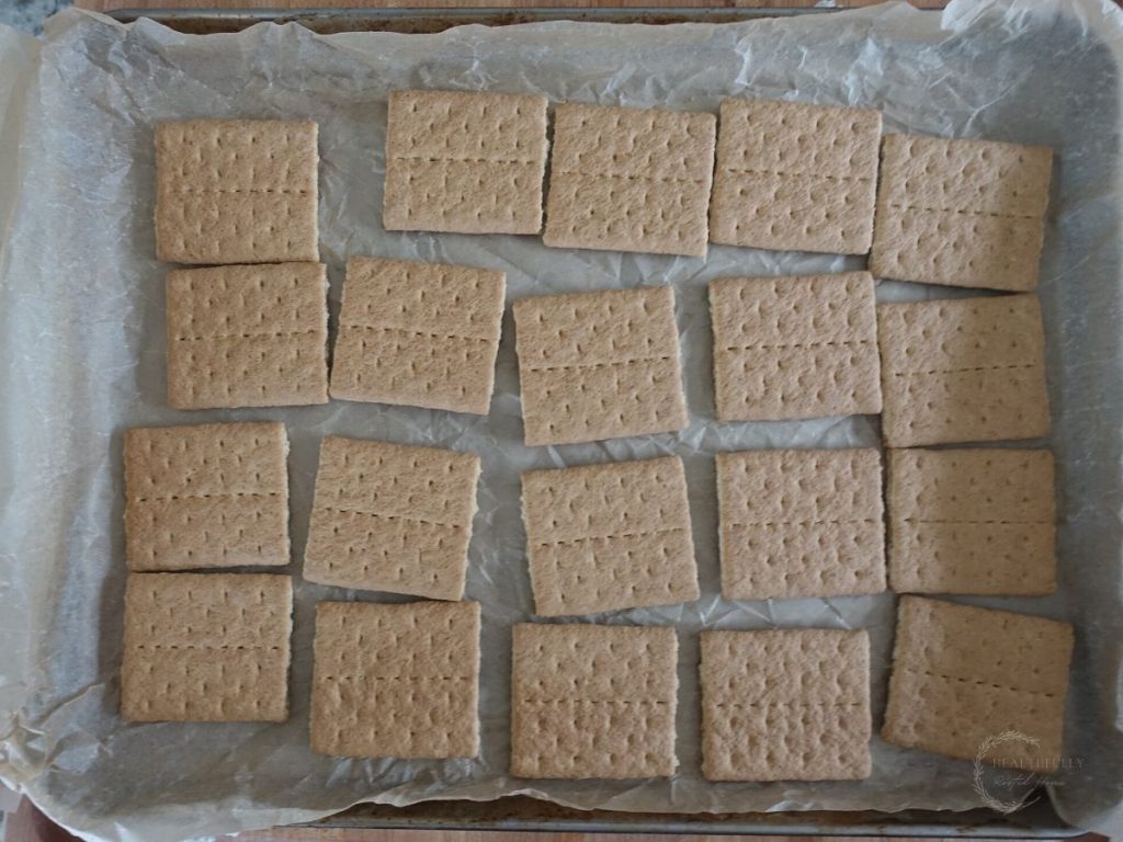 graham crackers lined up on a parchment lined baking sheet