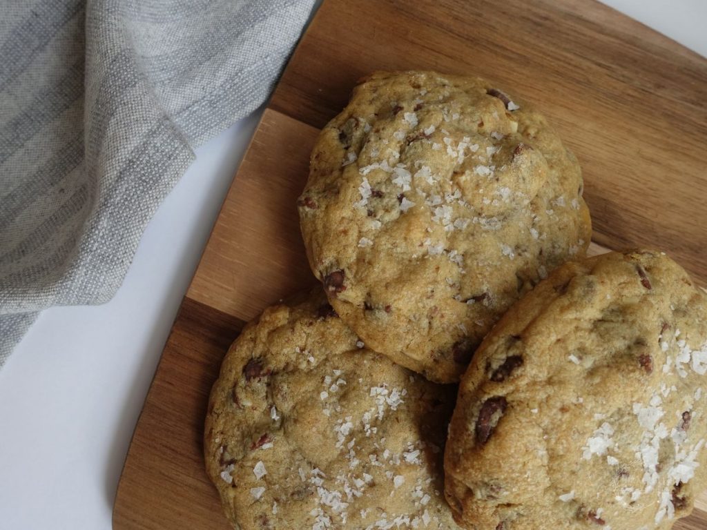 three cookies made without brown sugar on a wooden serving board with a tea towel underneath
