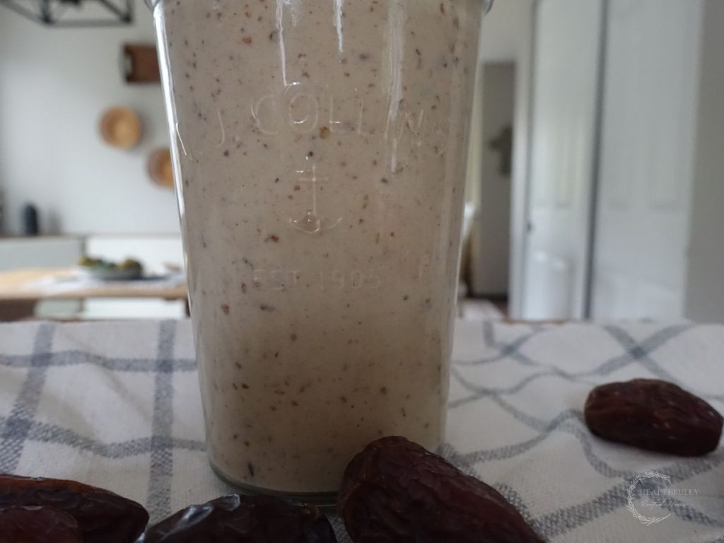 dates milkshake on a kitchen counter with a tea towel underneath and a bunch of dates around it