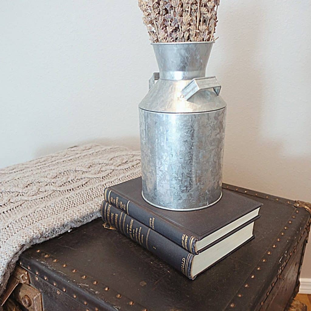 decluttering tips for hoarders lavender inside galvanized steel bucket on top of books and old suitcases next to a blanket 