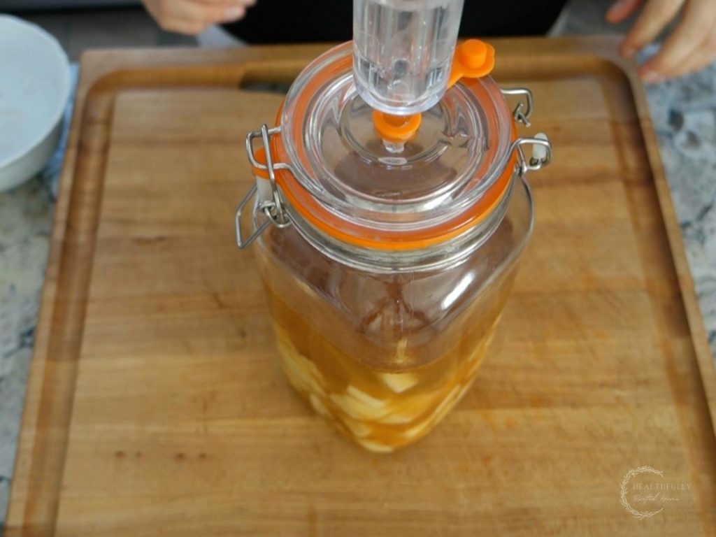 fermentation jar with pickle pipe with apples and brine inside ready to ferment on the counter for 2-5 days