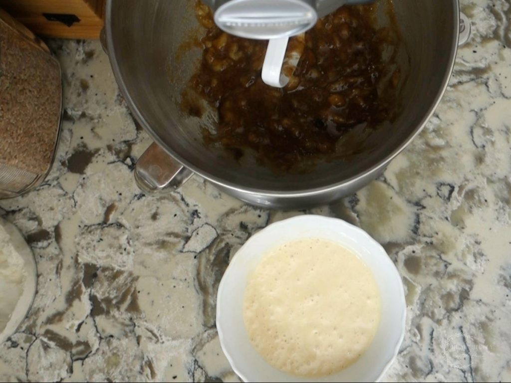 first step of making sourdough discard banana bread mixing in a stand mixer with a bowl of sourdough discard on the side