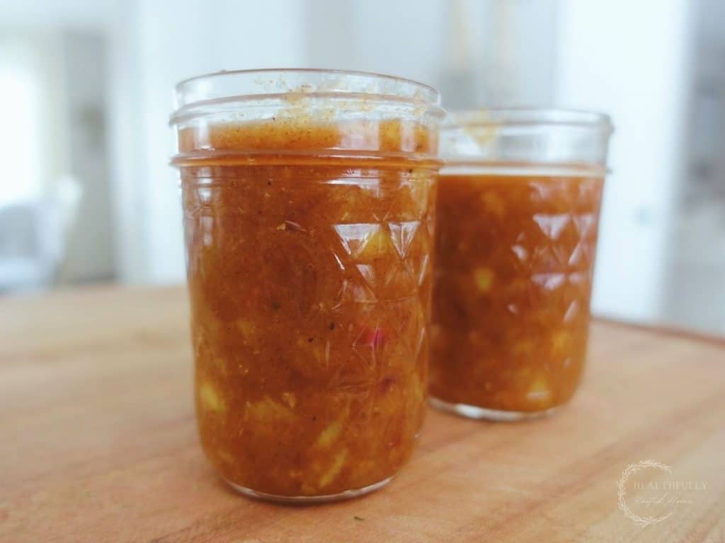 fermented mango chutney inside mason jars on top of a wooden cutting board