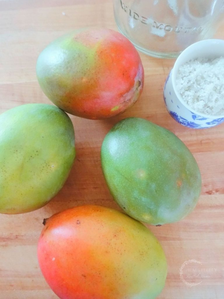 mangos on a wooden boos block cutting board next to sea salt and a mason jar