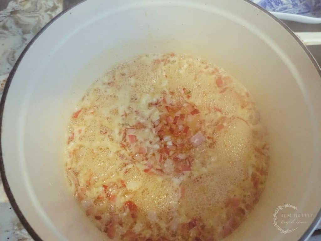 red onion honey and white wine vinegar in a white dutch oven with lots of bubbles