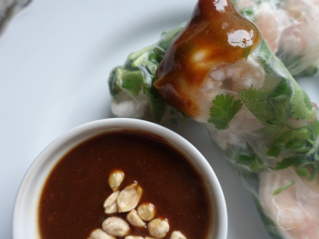spring rolls and hoisin peanut sauce with sauce on the spring roll stacked on top of another one